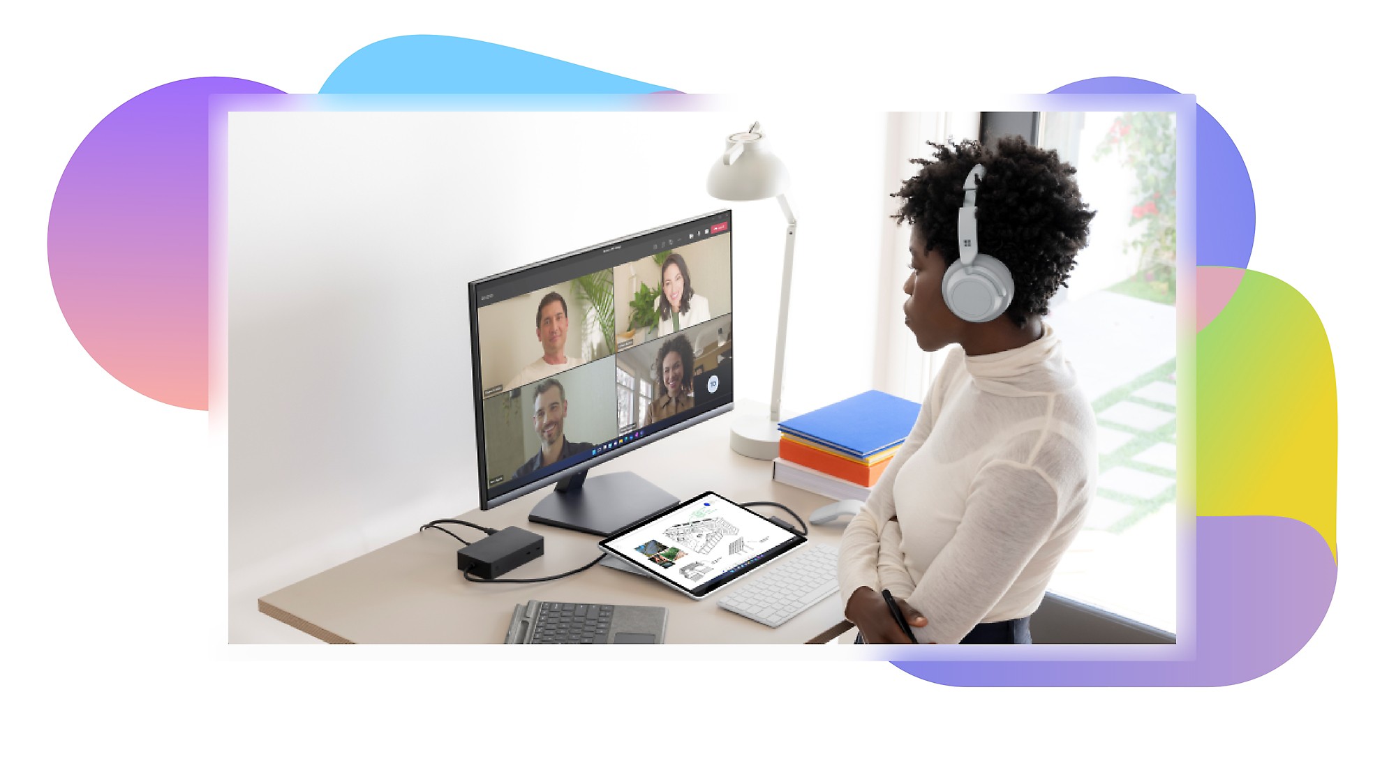 Una persona sentada en un escritorio con auriculares de diadema participa en una videollamada de Teams con otros cuatro participantes en un monitor de escritorio.
