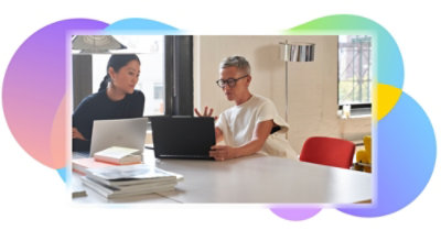 Due persone che collaborano sui portatili a un tavolo.