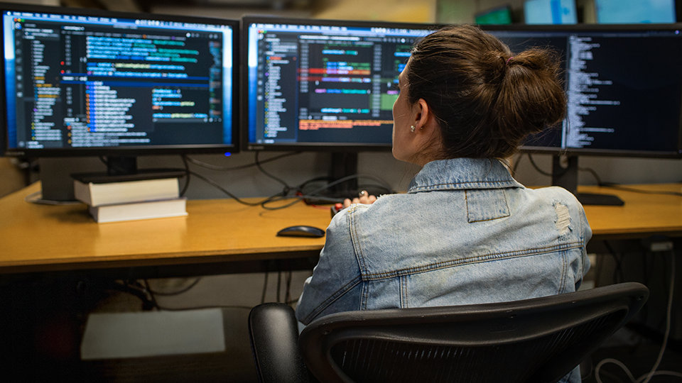 A developer codes on dual computer monitors.