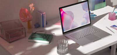 Ordinateur portable exécutant Windows 11 placé sur un bureau à côté de fleurs, d’un carnet et de lunettes