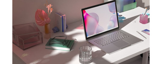 A laptop running Windows 11 sitting on a desk with flowers, notebooks and glasses.