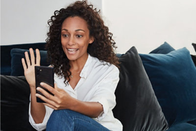 A person smiling and waving on a video call on their mobile phone