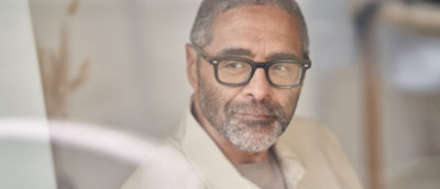 Person wearing glasses looking toward a computer screen.