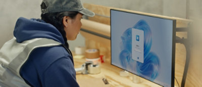 A person wearing a blue jacket looking at a computer screen.