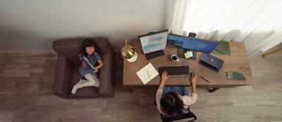 A person is working on a desk with two computer monitors, a keyboard, a coffee cup, and a few office supplies.