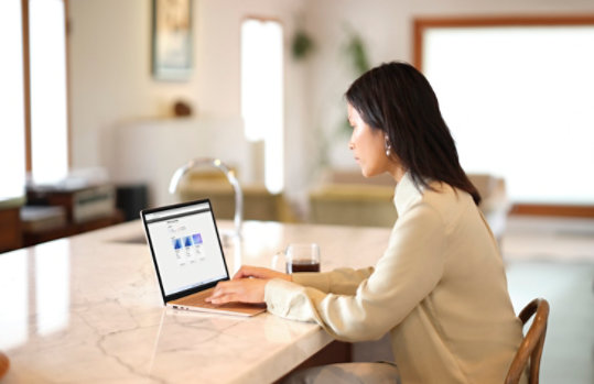 A woman using a laptop in a kitchen.