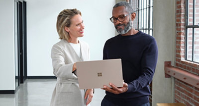 Two people standing in a hallway looking at a Surface Book.