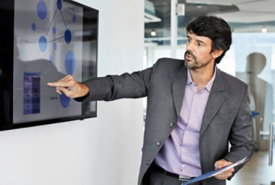 A man pointing at a screen displaying RENDIMENTO.