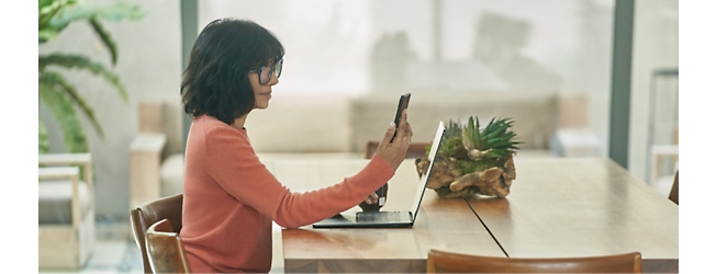 صورة لامرأة تجلس على طاولة عليها جهاز كمبيوتر محمول.
