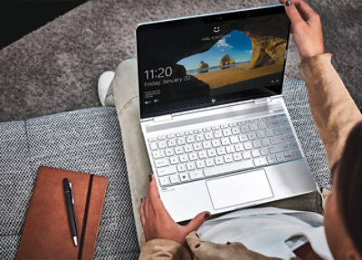 A person holding a white laptop displaying the time 11:20.