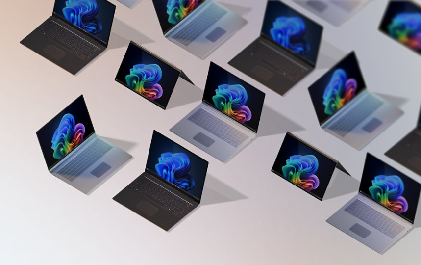 A group of 12 open Windows 11 Pro Edition and Windows PCs for business, some displaying the rainbow bloom image, some displaying the blue rainbow image, all seen from above against a gradient peach background