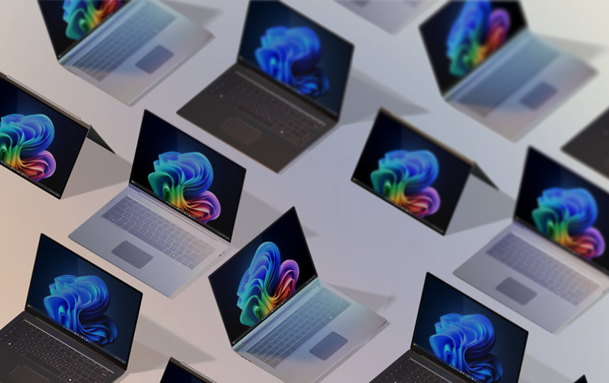A group of 12 open Windows 11 Pro Edition and Windows PCs for business, some displaying the rainbow bloom image, some displaying the blue rainbow image, all seen from above against a gradient peach background
