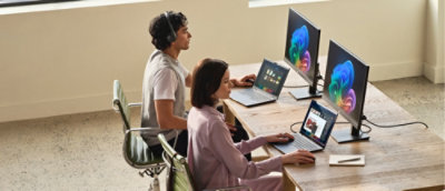 Two people sitting around a table with computers.