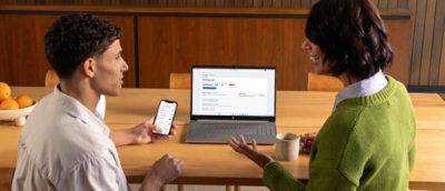 A group of people sitting at a table with a laptop and a phone.