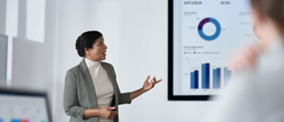 A woman in a suit standing in front of a screen.
