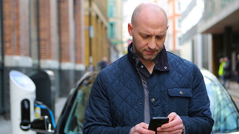 Male in navy-blue jacket reading from his mobile phone