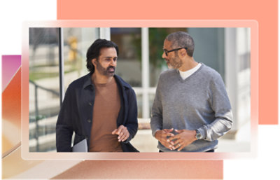 A couple of men talking, one in a brown shirt, another in a grey sweater.