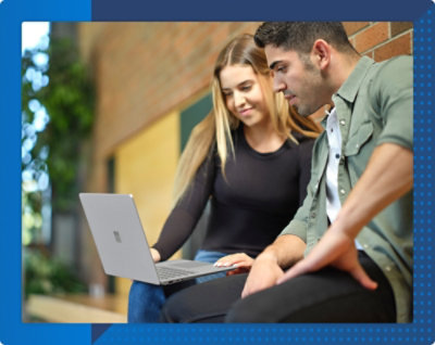 Two individuals sitting and looking at a laptop screen together.