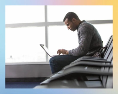 A person sitting on a bench using a computer.