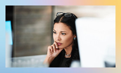 A close-up of a woman with her hand on her chin.