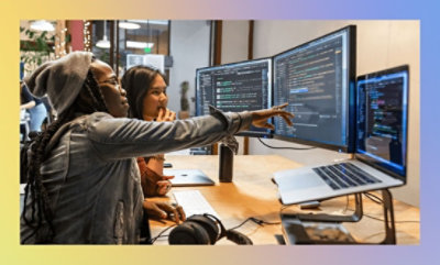 Une femme pointe du doigt un écran d'ordinateur et discute avec une autre femme.