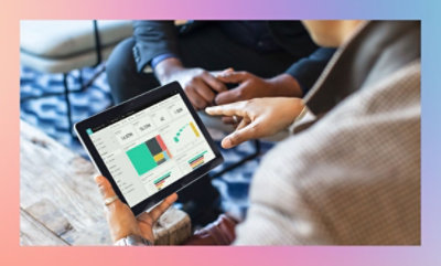 Two people reviewing a bar graph on a tablet.