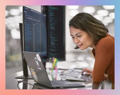 Person working on a laptop with code on the screen in an office environment.