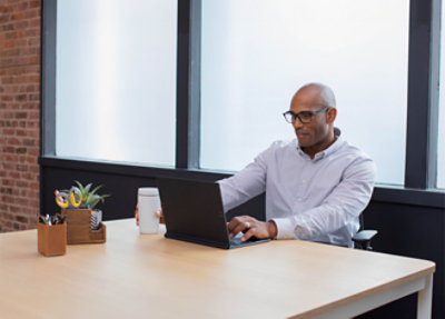 A man sitting at a desk using a laptop.