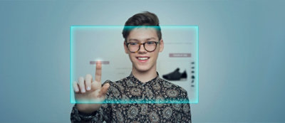 A person wearing glasses and a patterned shirt is smiling