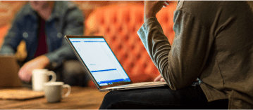 Eine Person, die auf einer Couch sitzt und einen Laptop benutzt