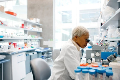 A scientist looking through a microscope in a lab