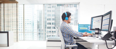 ヘッドホンを着け、デスクに向かって座っている男性。