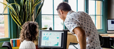 En una oficina, dos personas observan gráficos de datos en la pantalla de un ordenador.