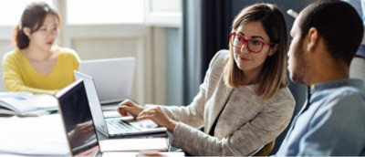 Two individuals collaborating on a laptop in an office setting.