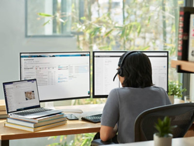 デスクで複数の画面を使って作業している人。