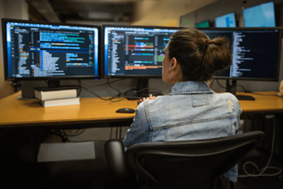 A person working at their desk with multiple screens