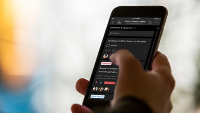 Eine Hand, die ein Mobiltelefon hält, auf dem Aufgaben angezeigt werden