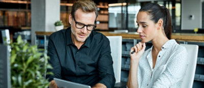 Two people working on laptop in office