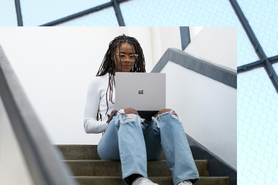 A woman works on her Platinum Surface Laptop 5 in a staircase.