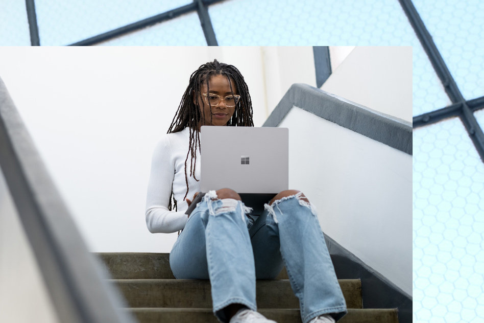 Uma mulher a trabalhar no seu Surface Laptop 5 em Platina numa escadaria.