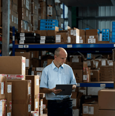 Seseorang berdiri di gudang sambil memegang tablet di tangan