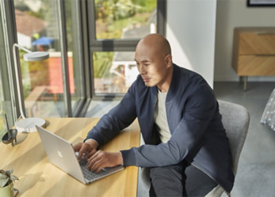 A man sitting at a table using a laptop.
