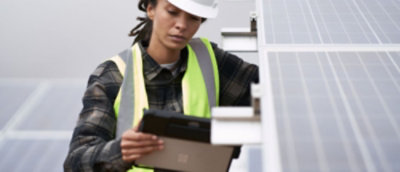 Field engineer using a Surface tablet while inspecting solar panels.