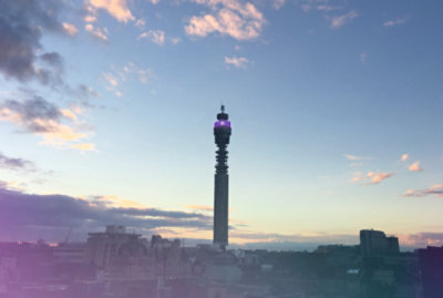 The BT Tower in London at dusk, with a partly cloudy sky and light from the setting sun casting a warm glow.