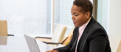A business woman using a laptop in a conference room.