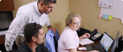 一群人在辦公室中看著一部膝上型電腦。