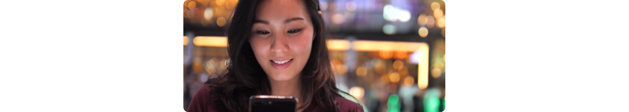 Uma jovem mulher asiática a olhar para o seu telemóvel.