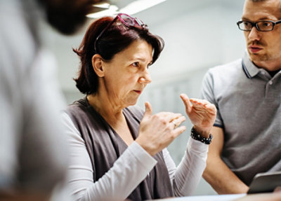 A woman with glasses on her head talking to a man.