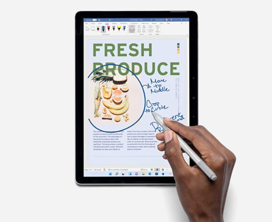 A person uses Surface Pro Pen to make editorial notes on a draft farmer's market catalog using Ink Editor in Microsoft Word. 