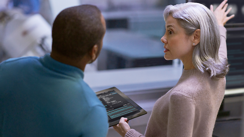 Um homem a falar com a mulher a segurar um tablet na mão